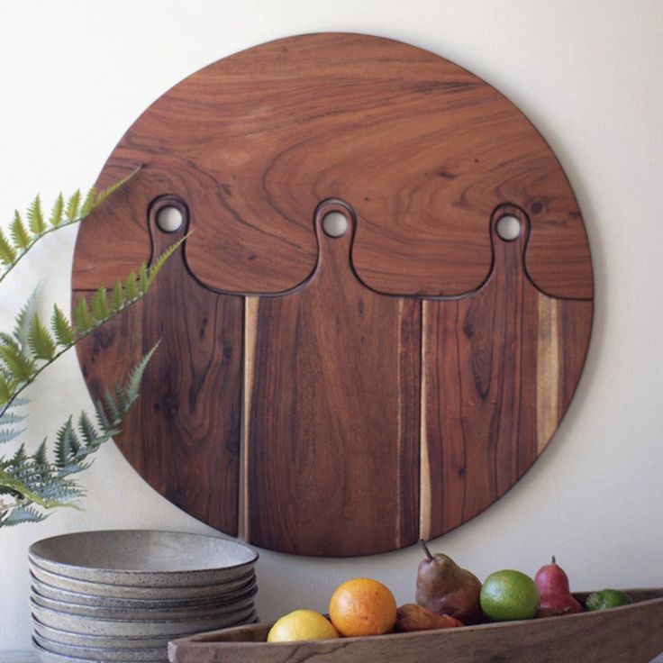 a wooden cutting board sitting on top of a table next to plates and bowls filled with fruit