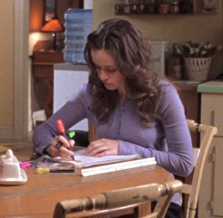 a woman sitting at a kitchen table writing