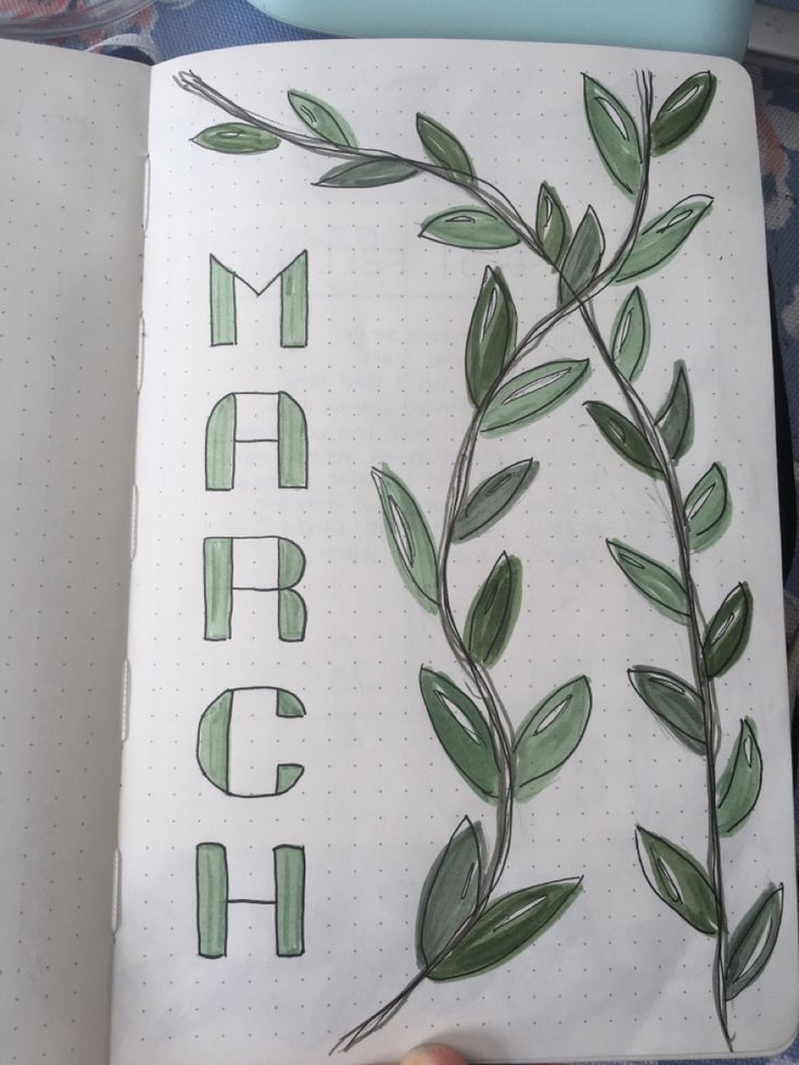 an open notebook with green leaves and the word march written in cursive writing