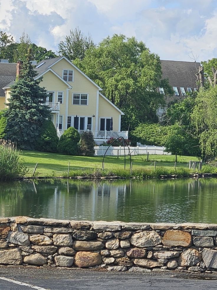 a large white house sitting on top of a lush green field next to a lake