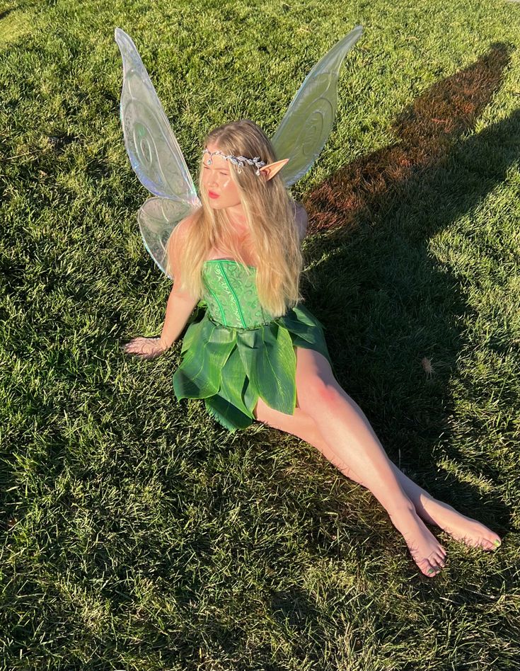 a woman dressed as tinkerbell laying in the grass