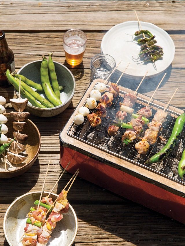 there are many food items on the grill and plates with skewered meats