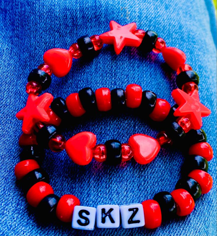 two red and black bracelets that say sk2 with stars on the top one