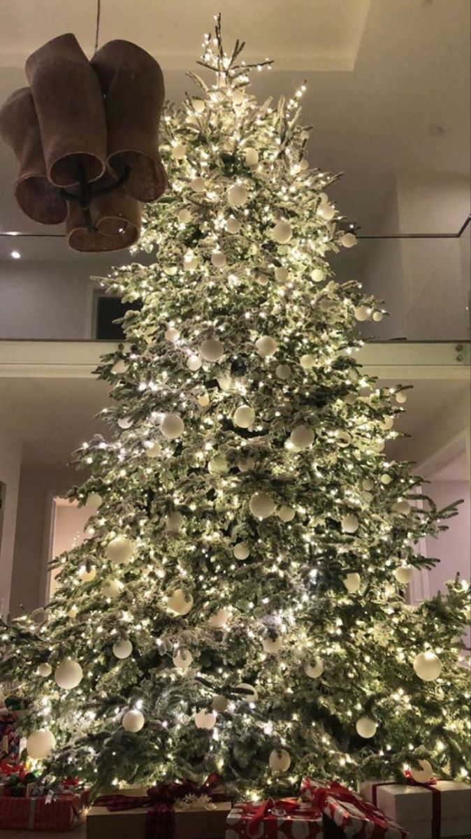 a large christmas tree in the middle of a room with lights and presents on it