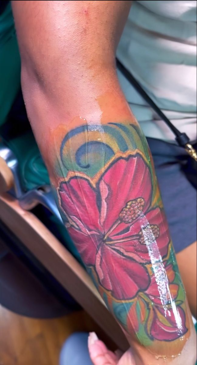 a person with a flower tattoo on their arm and leg is holding a cell phone