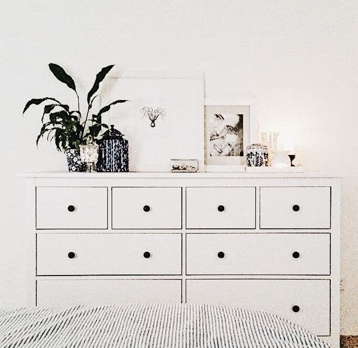 a white dresser sitting next to a wall with pictures on it's top shelf