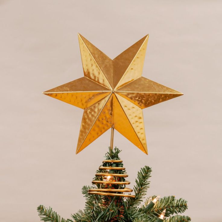 a gold star hanging from the top of a christmas tree