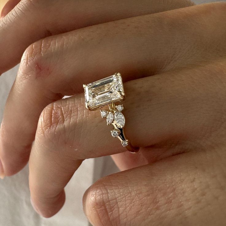 a woman's hand with a diamond ring on top of her finger and an engagement band