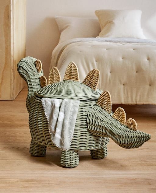 an elephant shaped basket sitting on top of a wooden floor next to a white bed