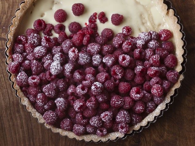 raspberries and cream in a pie dish on a wooden table