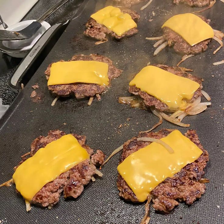 hamburger patties covered in cheese on a grill