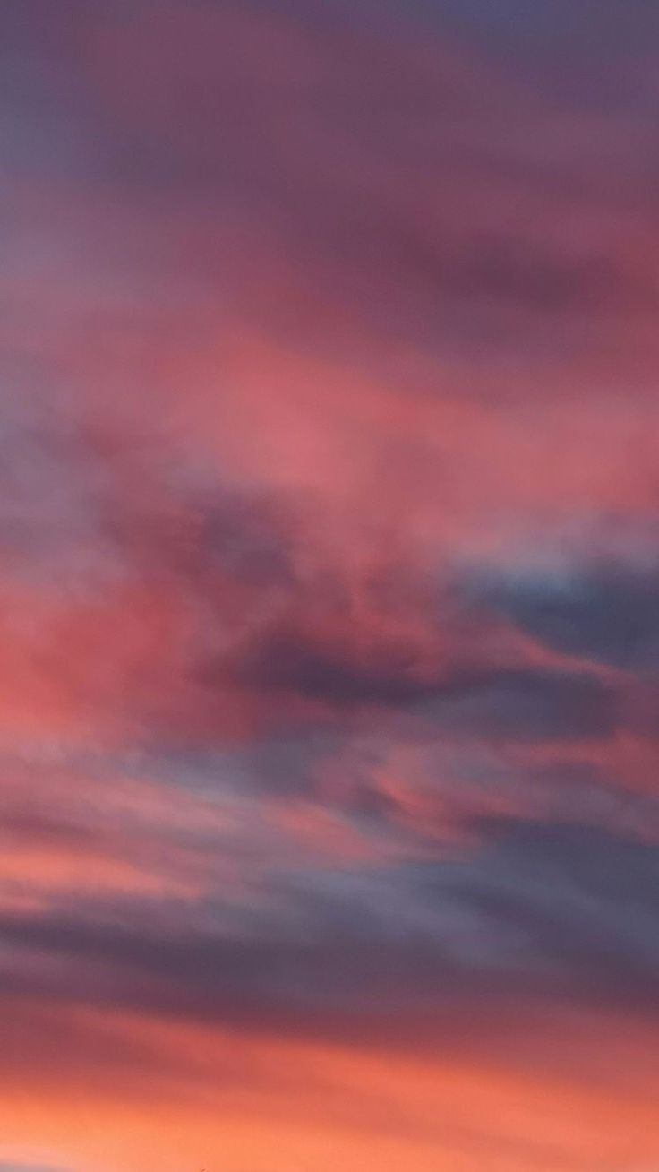 an airplane is flying in the sky at sunset or dawn with pink and blue clouds