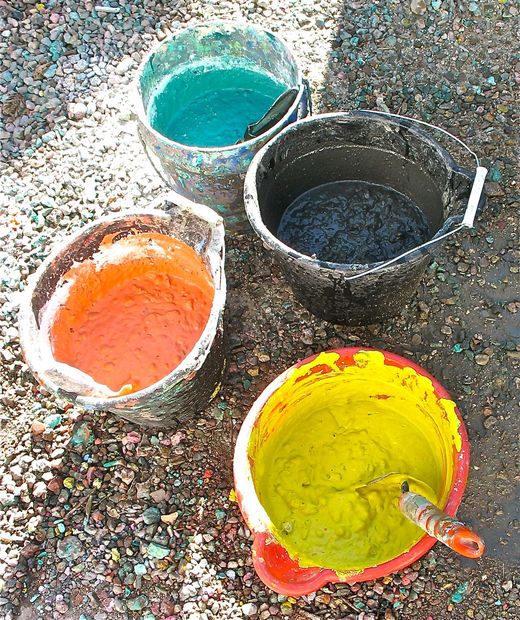 three buckets filled with different colored paint sitting on the ground