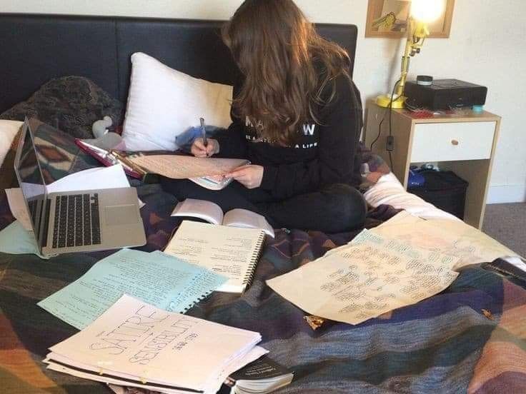 a person sitting on a bed with lots of papers and notebooks in front of them