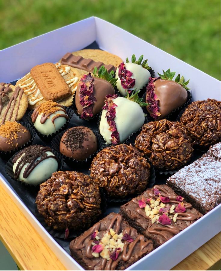 a box filled with lots of different types of cookies and pastries on top of a wooden table