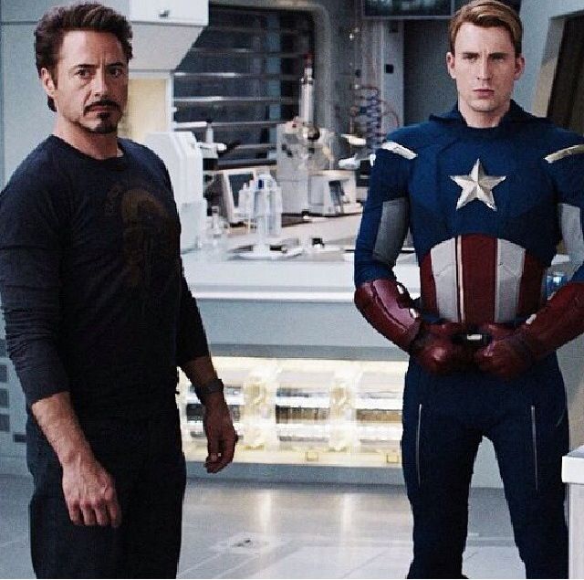 two men dressed as captain america standing next to each other in front of a kitchen