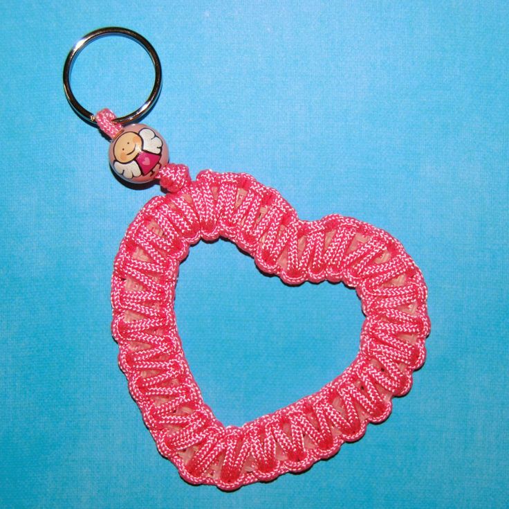 a pink heart shaped keychain with a button on the end and a beaded cord attached to it