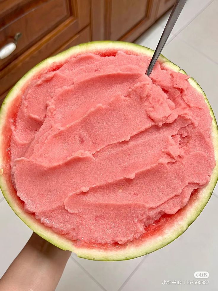 a person holding up a watermelon slice with a knife in it