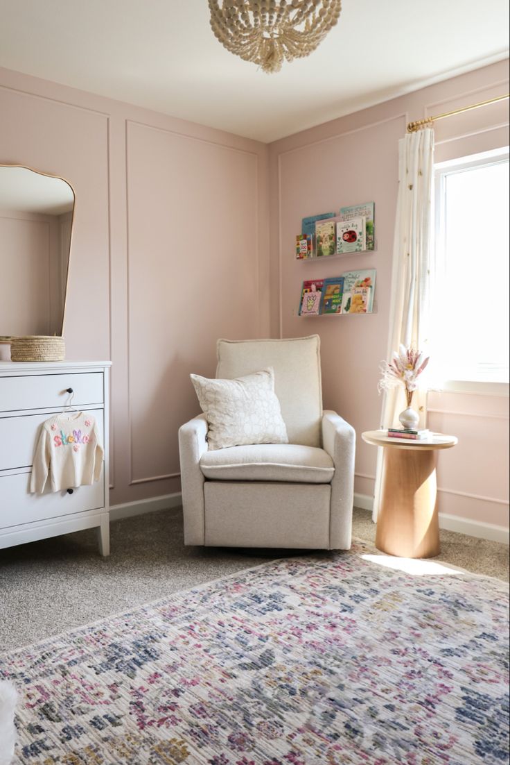 a living room with pink walls and a white chair next to a mirror on the wall