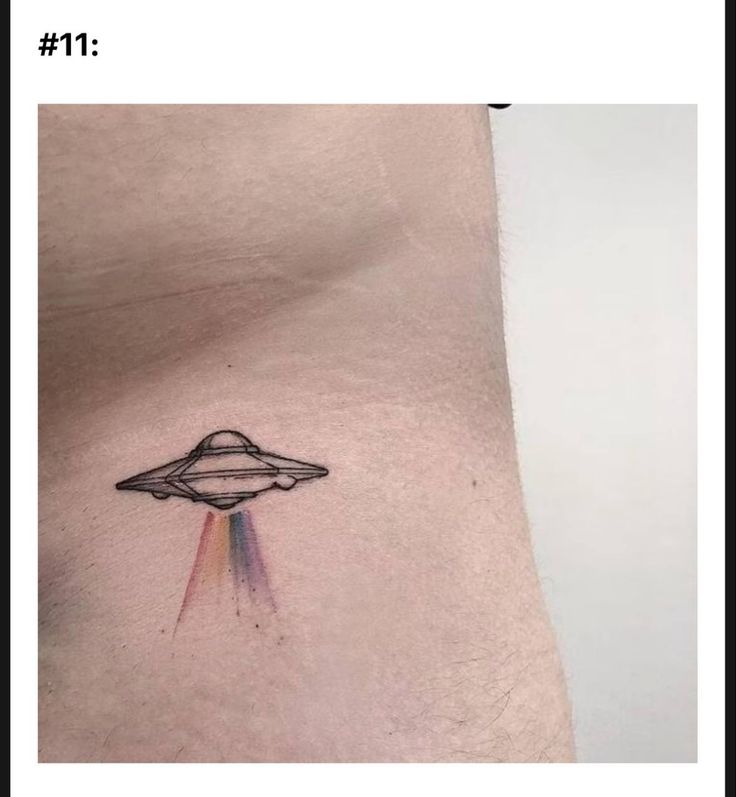 a man's stomach with an alien tattoo on it