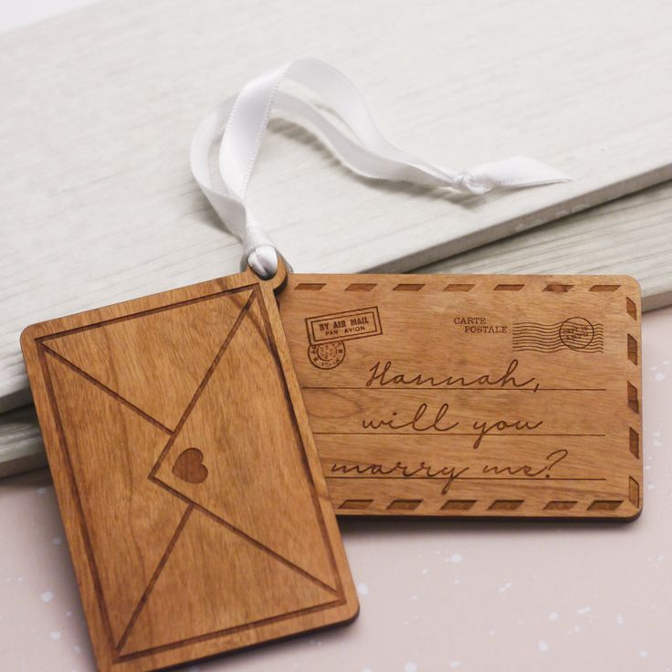 two wooden tags with writing on them are sitting next to each other and one has a white ribbon around it