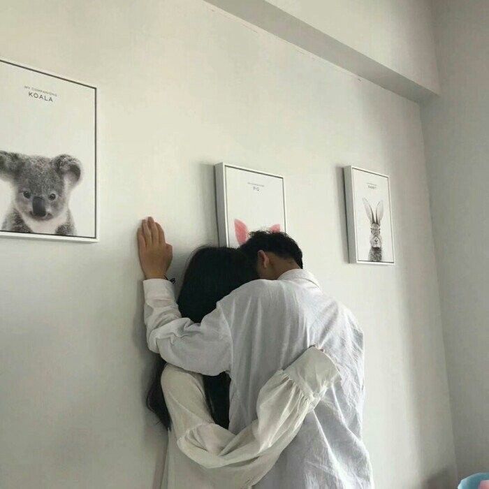 two people hugging each other in front of pictures on the wall