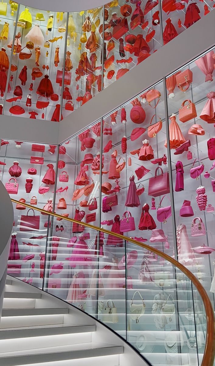 there are many pink and orange items on display in the glass case at the top of the stairs