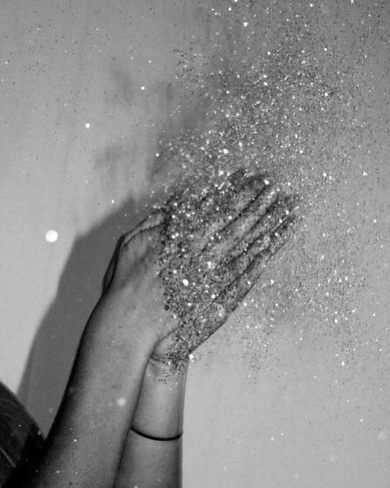 two hands reaching up into the air with glitter all over them