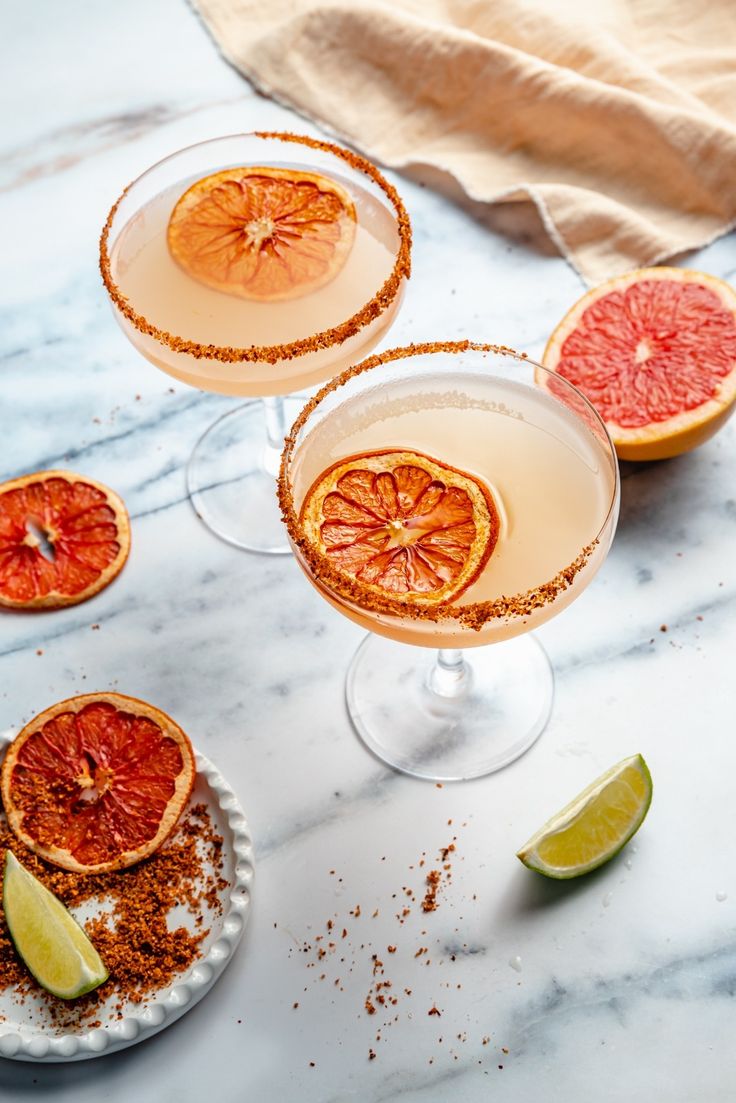 three glasses filled with grapefruit margaritas and garnish