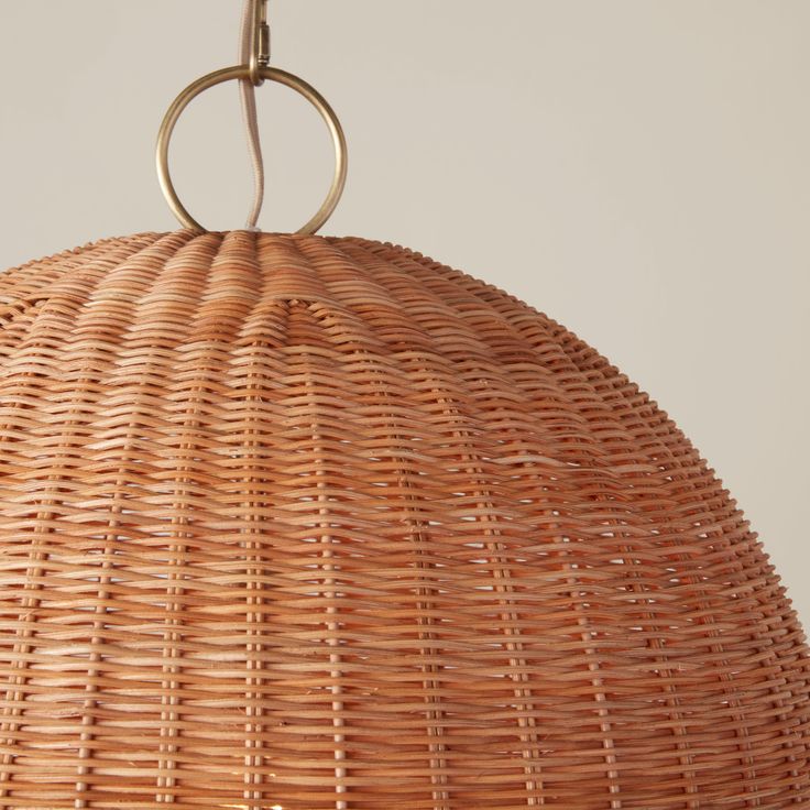 the light fixture is made out of wicker and has a metal ring hanging from it