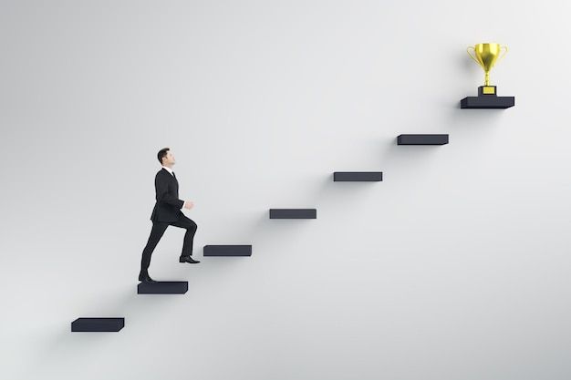 a man in a suit is walking up the stairs with a golden trophy on top