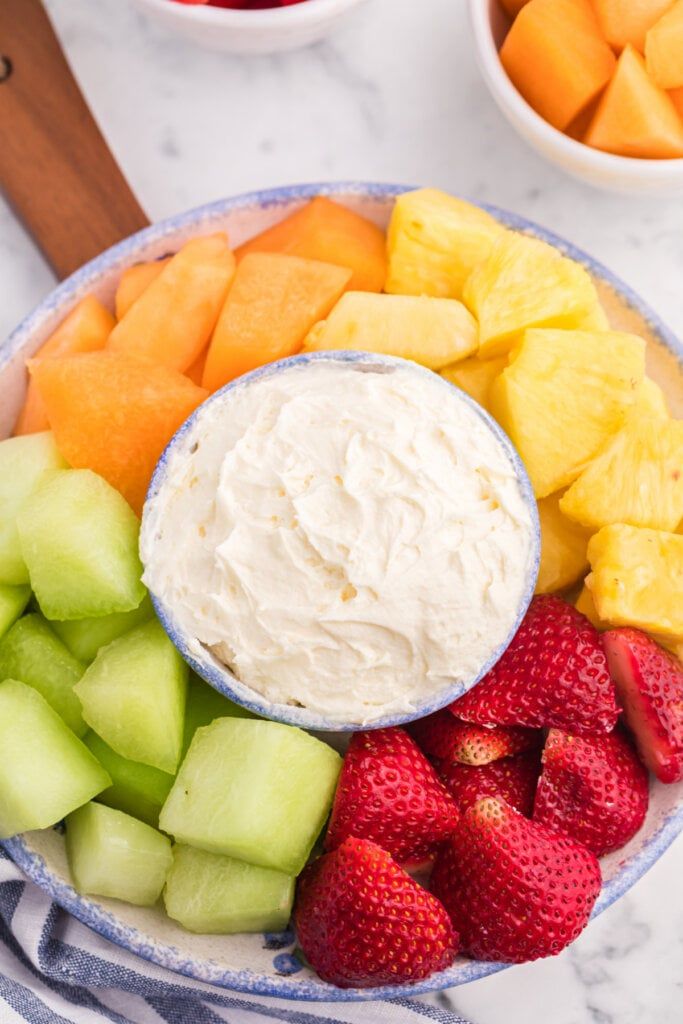 a bowl filled with fruit and dip on top of a table