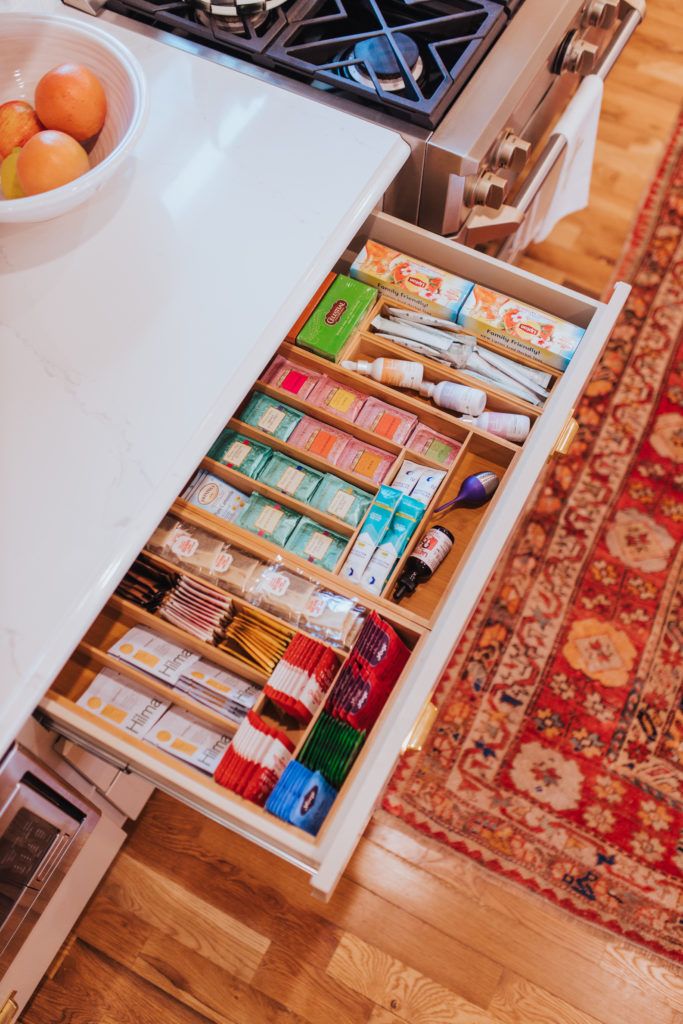 an open drawer in the middle of a kitchen counter filled with spices and other items