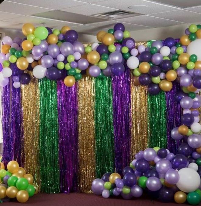 balloons and streamers are hanging from the ceiling in an office space with purple, green, and gold decorations