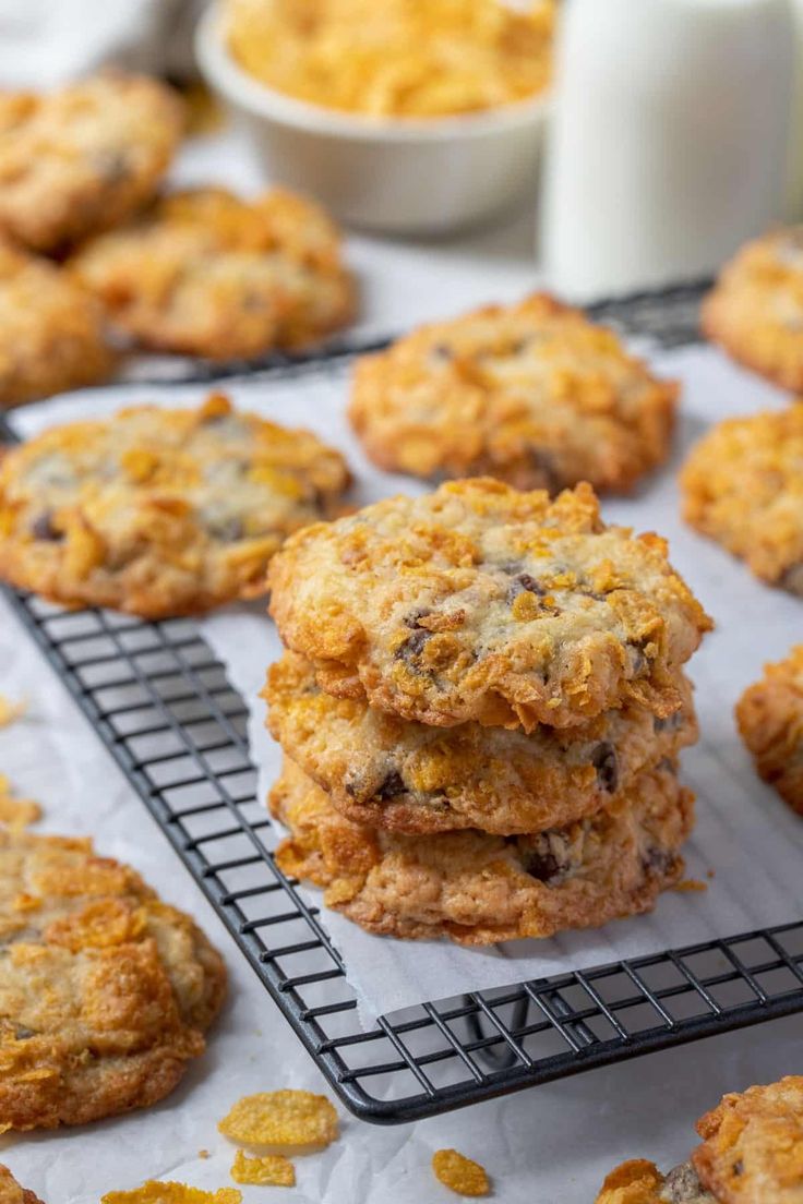 several cookies on a cooling rack next to a glass of milk and some orange zest