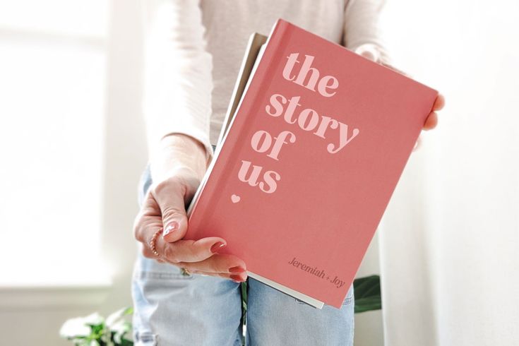 a woman holding a pink book with the words the story of us written on it