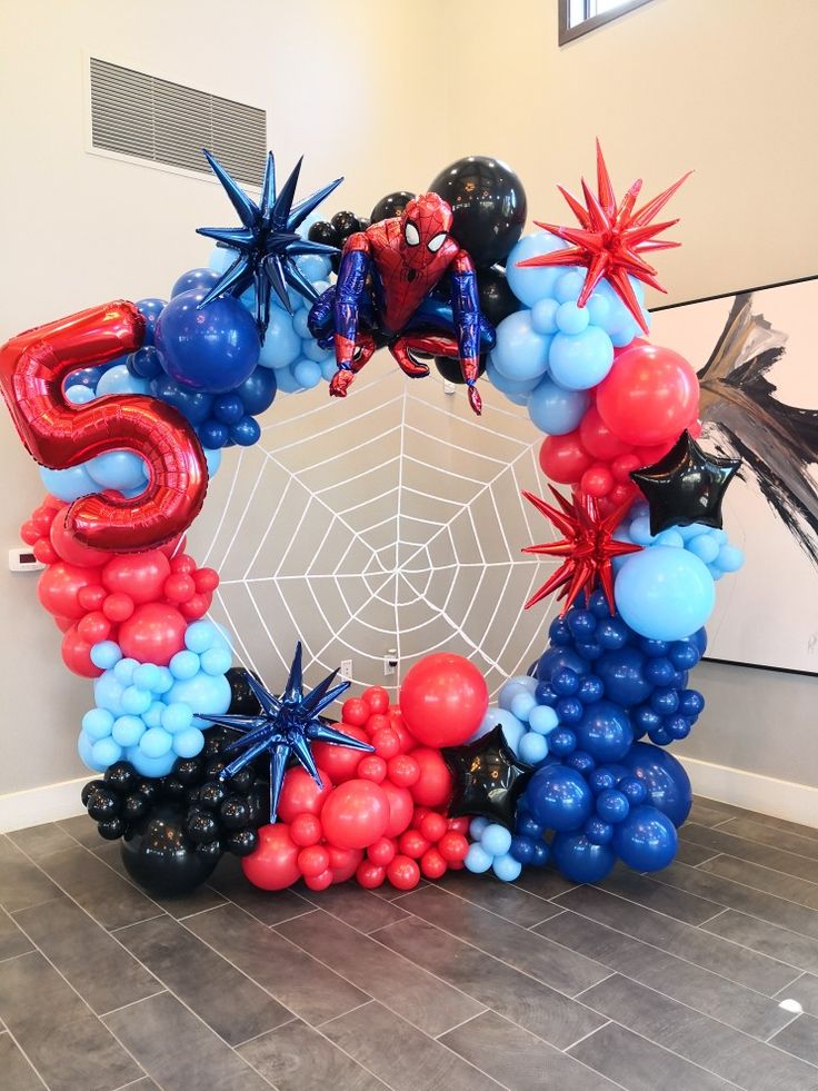 the balloon arch is decorated with balloons and spiderman decorations for an entrance to a party