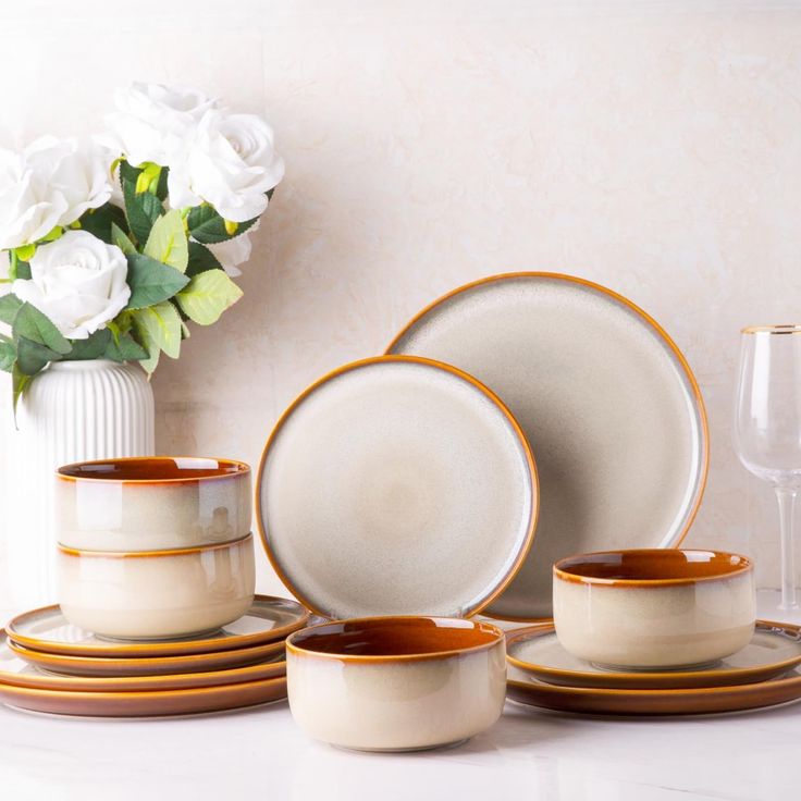 a table topped with plates and cups next to a vase filled with flowers