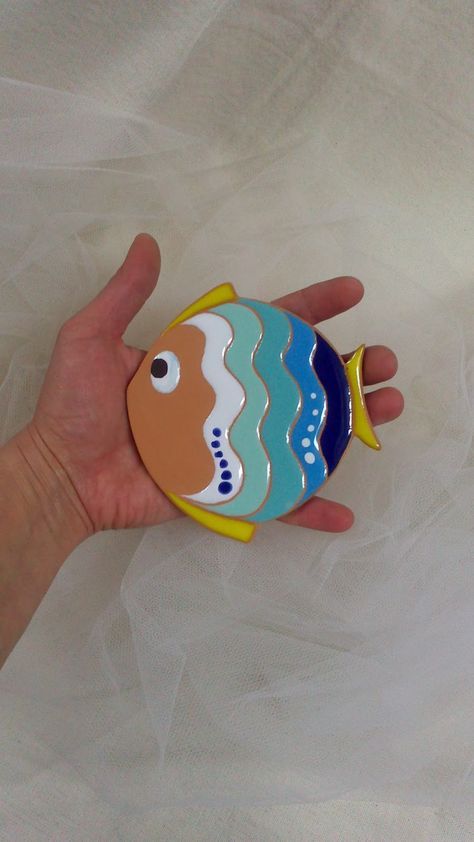 a hand is holding a colorful fish brooch