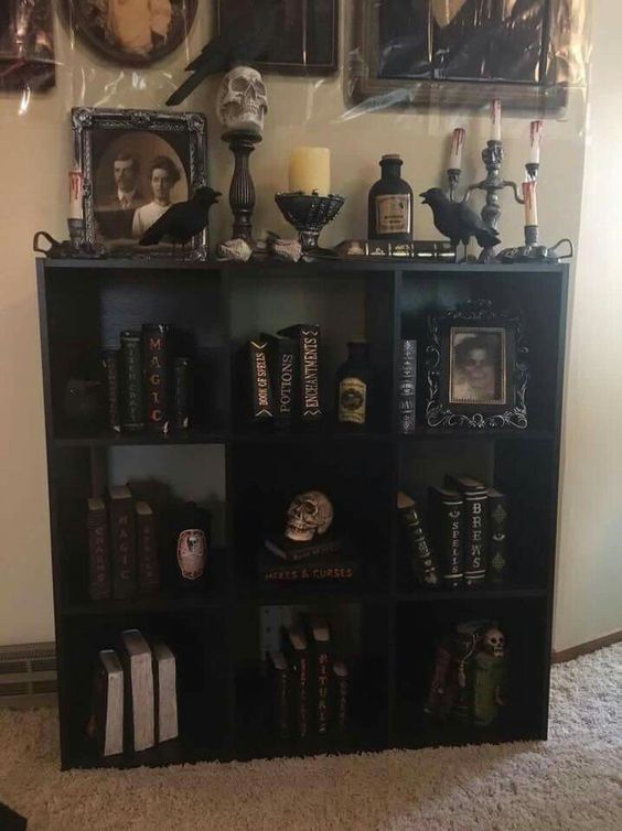 a black book shelf with pictures and candles on it in front of a white wall