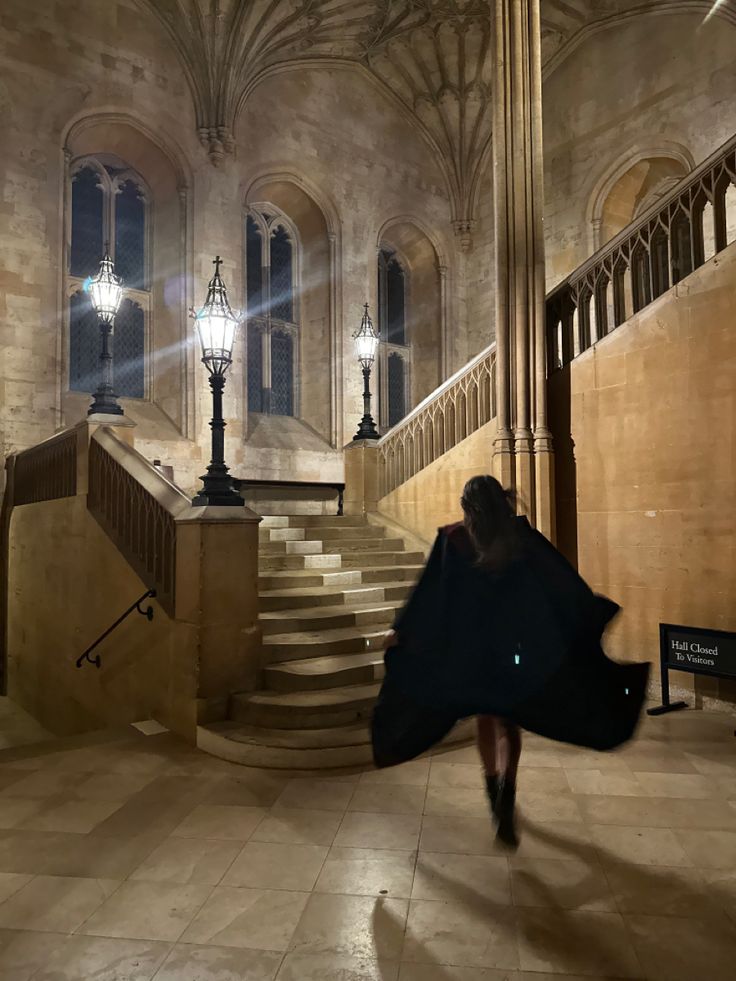 a woman is walking down the stairs in an old building with light shining on her