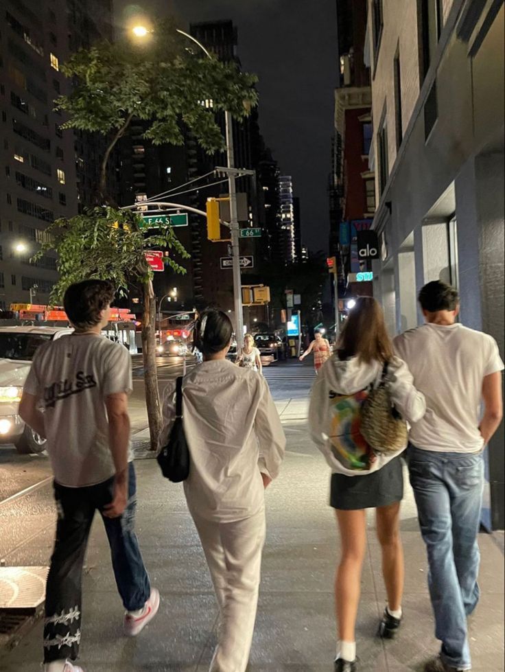 three people walking down the street at night