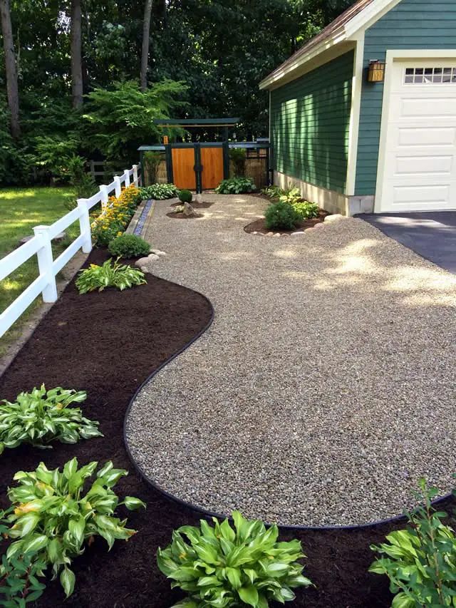 a driveway with gravel and plants around it