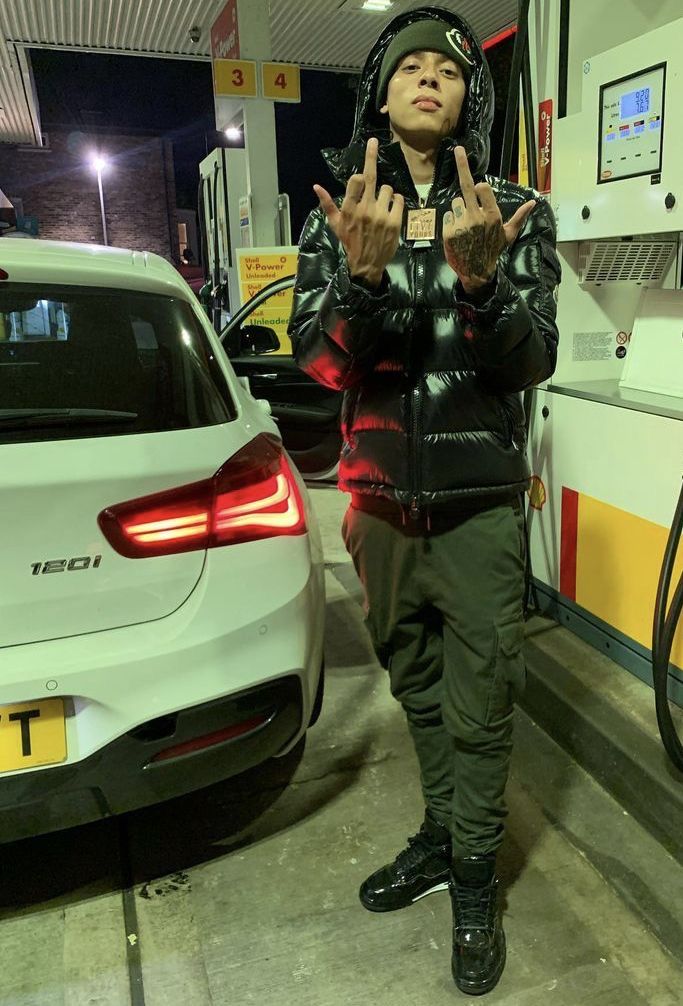 a man standing in front of a gas pump giving the peace sign with both hands