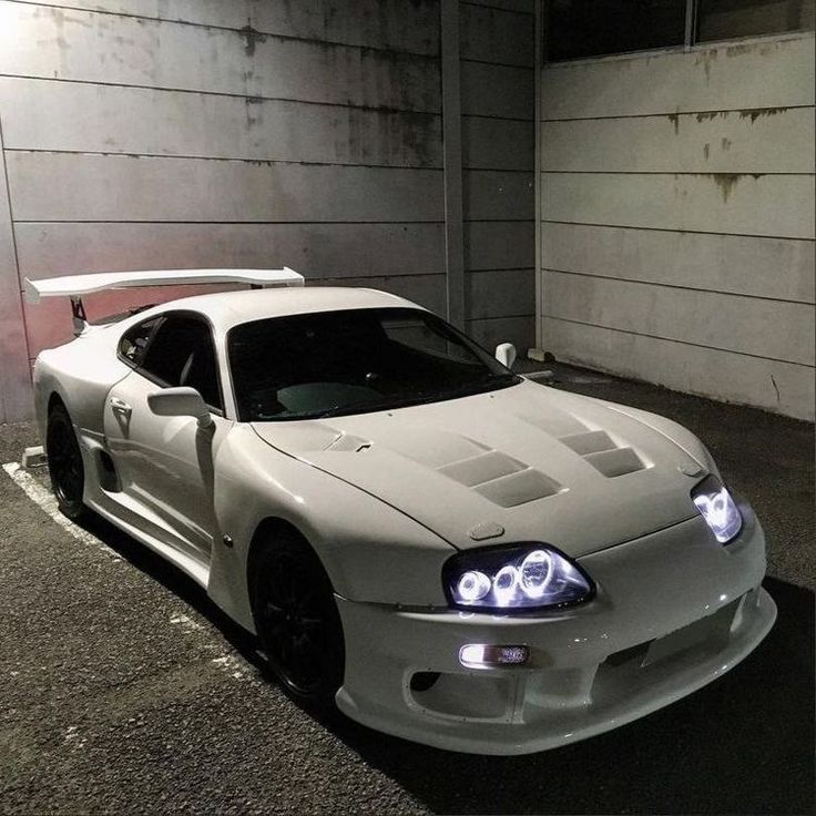 a white sports car parked in an empty parking garage with no one around it and the lights on