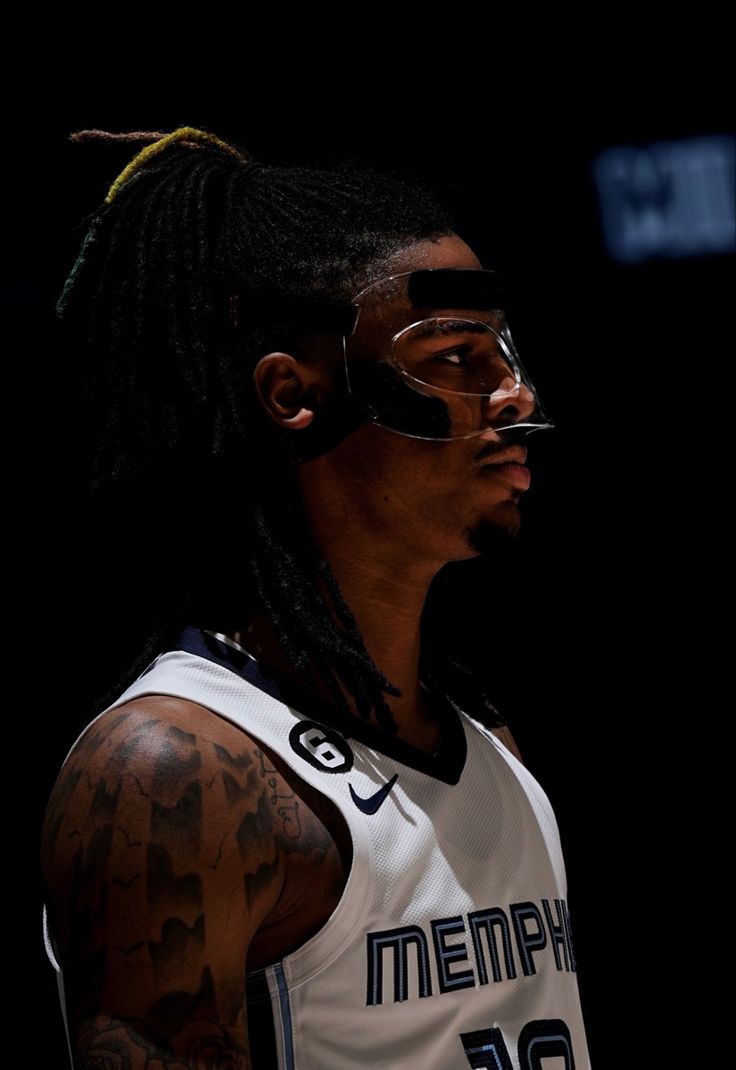 a man with dreadlocks wearing a white jersey and black glasses on his face