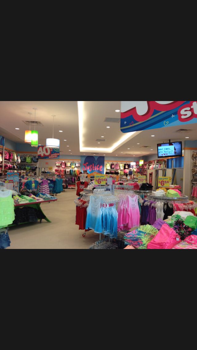 the inside of a clothing store with clothes on racks and t - shirts for sale