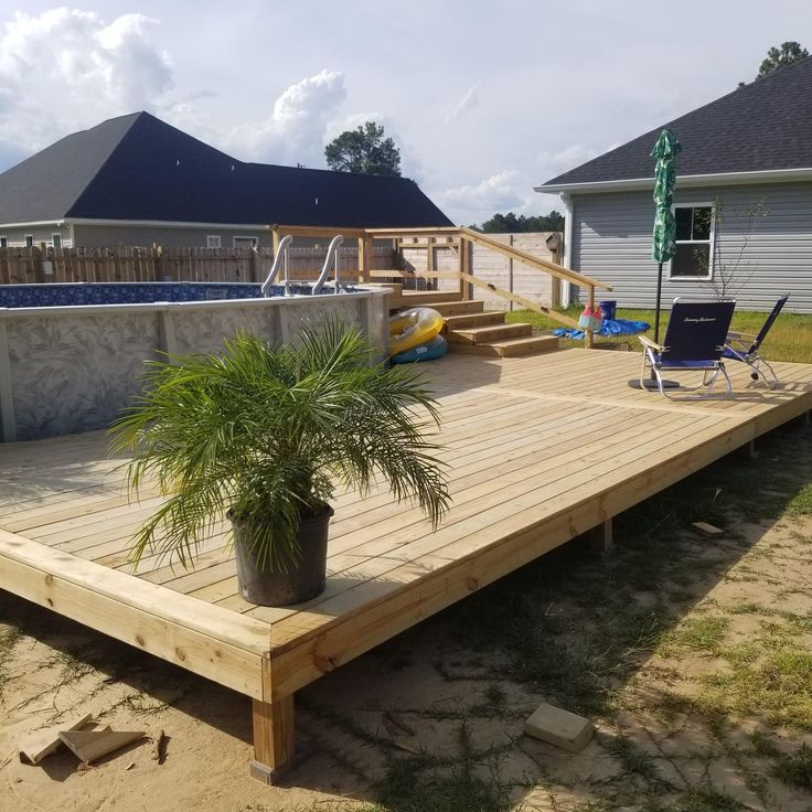 a wooden deck with a potted plant next to it and a hot tub in the background