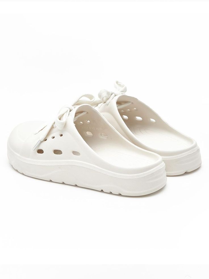 a pair of white shoes with holes on the bottom and soles, sitting against a white background