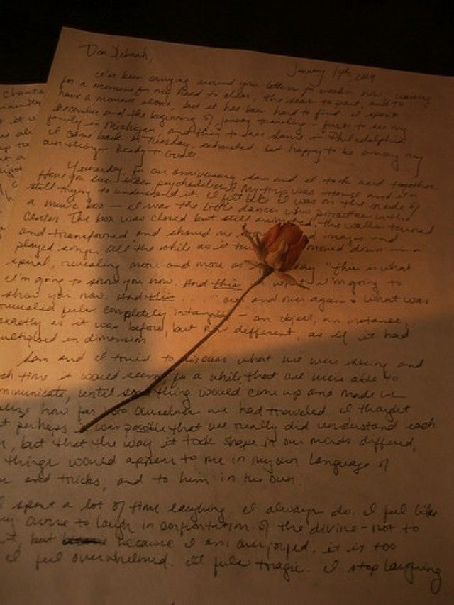 a piece of paper with writing and a rose on it, sitting on a table